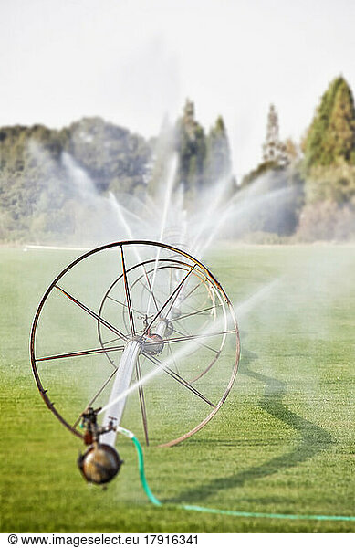 Water hoses on round frames spraying water jets in a field  commercial horticultural sprinklers and irrigation.
