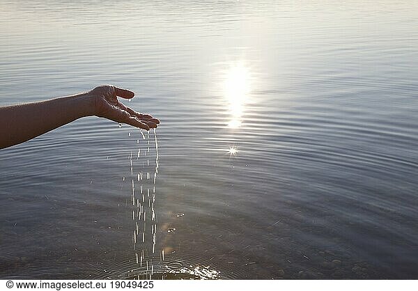 Water pours from hands into tranquil lake