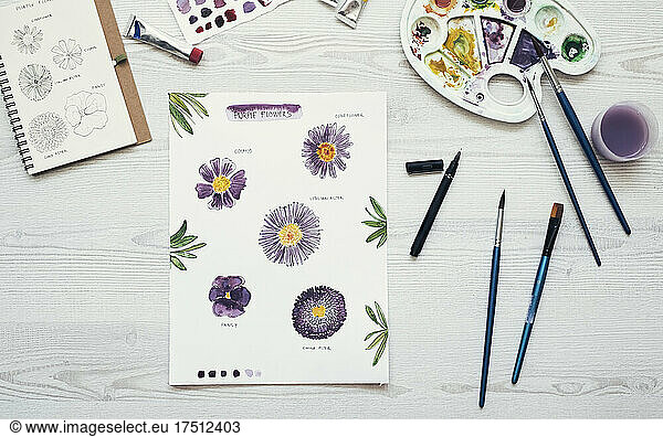 Watercolor painting of purple flowers on the desk  top view
