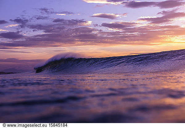 Wave breaking close to the shores of France with sunset colors.