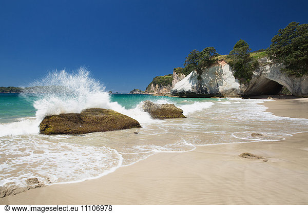 Waves splashing against large rocks on the beach in Cathedral Cove  Coromandel  Waikato  North Island  New Zealand  Pacific