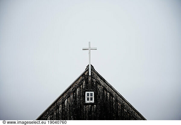 Weathered wooden church with cross on roof against overcast sky