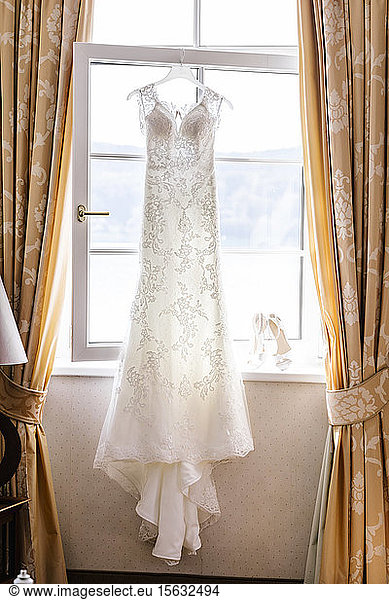Wedding dress hanging in front of window at home