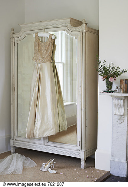 Wedding gown hanging from wardrobe