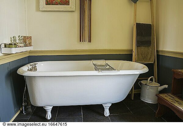 Weiße Klauenfuß-Badewanne im Hauptbadezimmer mit schwarzem Keramikfliesenboden in einem alten Feldsteinhaus im Landhausstil von 1841  Quebec  Kanada. Dieses Bild ist freigegebenes Eigentum. CUPR0355.