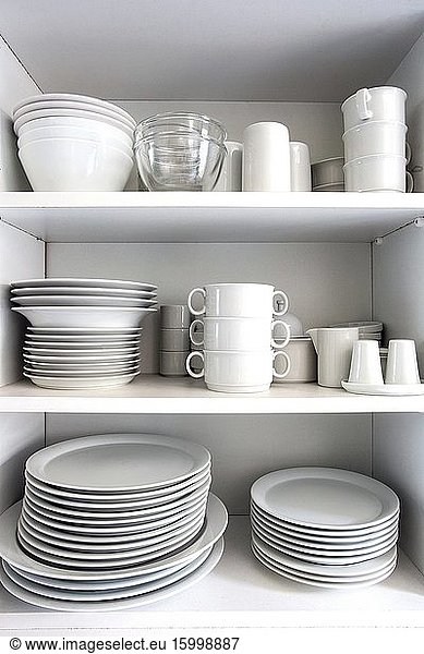 Weißer Schrank mit weißem Geschirr in der Küche  verschiedene saubere Teller in Nahaufnahme.