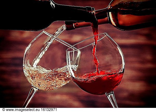 Weiß- und Rotwein in Gläsern auf hölzernem Hintergrund.