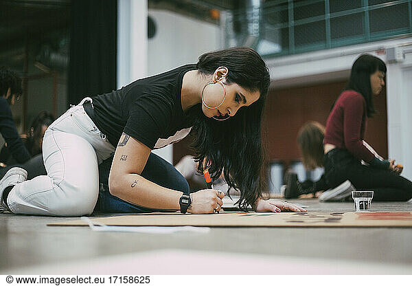 Weibliche Aktivistin bereitet Schild vor  während sie in einem Gebäude sitzt  um gegen soziale Probleme zu protestieren