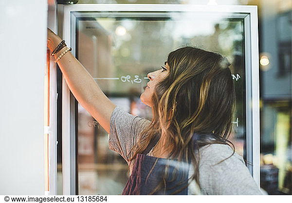 Weibliche Angestellte sucht im Kühlschrank eines Feinkostladens