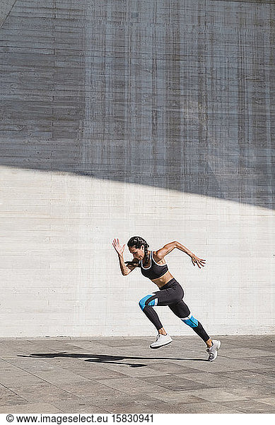Weibliche Athletin läuft auf Beton vertikal