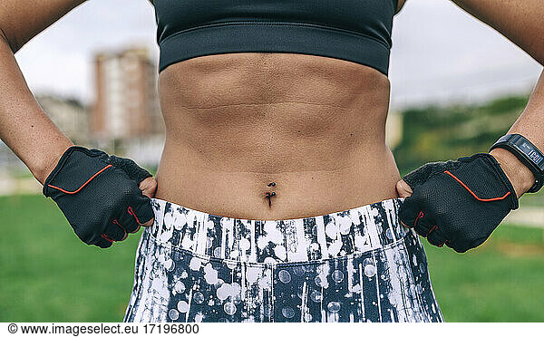 Weibliche Athletin posiert und zeigt Bauchmuskeln