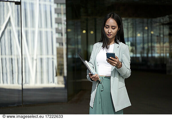 Weibliche Berufstätige senden Textnachrichten auf dem Mobiltelefon