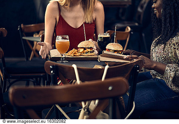 Weibliche Freunde essen einen Burger in einer Kneipe