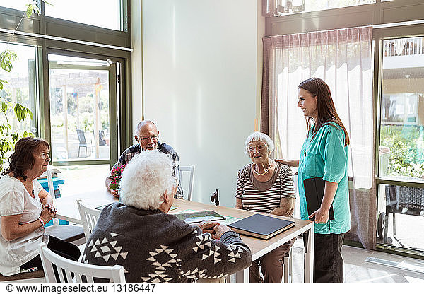 Weibliche Gesundheitshelferin im Gespräch mit älteren Menschen im Pflegeheim