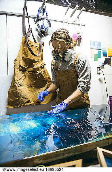 Weibliche Harzkünstlerin arbeitet mit ihren Händen an einem großen Kunstwerk