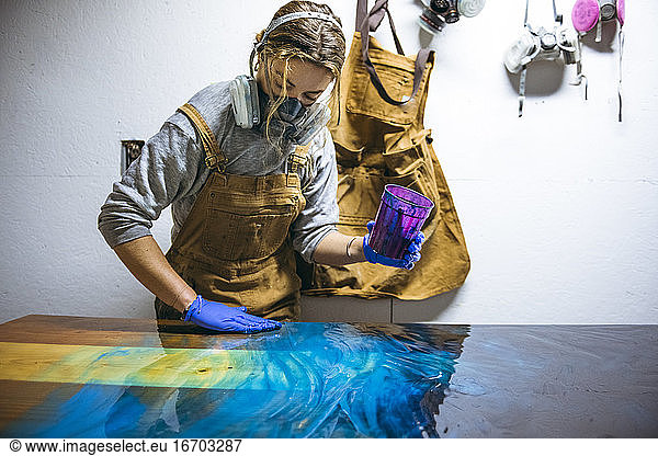 Weibliche Harzkünstlerin arbeitet mit ihren Händen an einem großen Kunstwerk