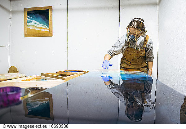 Weibliche Harzkünstlerin benutzt ihre Hände  um ihr Kunstwerk zu perfektionieren