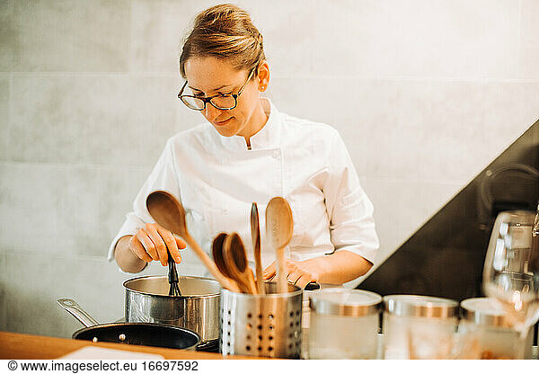 Weibliche Köchin rührt Essen um  während sie an der Küchentheke steht