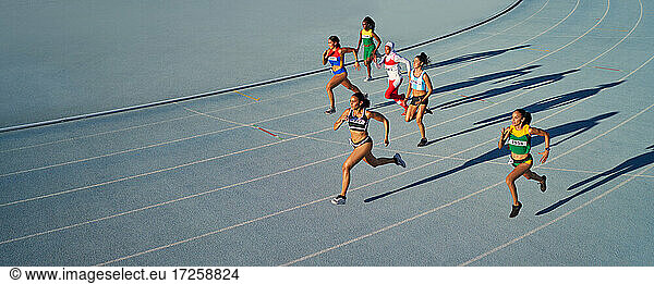 Weibliche Leichtathleten laufen im Rennen auf blauer Bahn