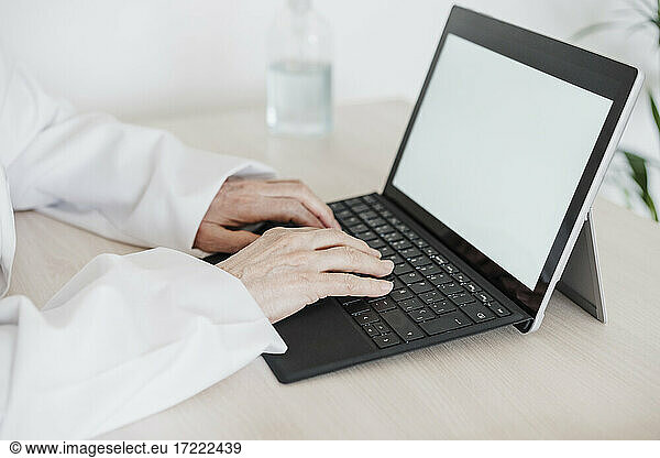 Weibliche medizinische Fachkraft  die ein digitales Tablet am Schreibtisch in einer medizinischen Klinik benutzt