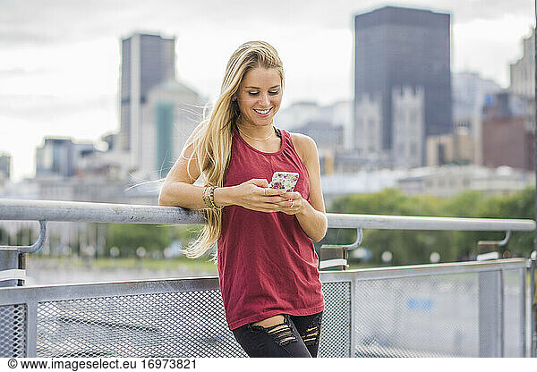 Weibliche Millennials mit Smartphone und Stadt im Hintergrund