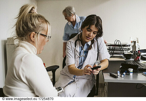 Weibliche Mitarbeiterin im Gesundheitswesen diskutiert mit einem Patienten über ein Glaukomgerät in einer medizinischen Klinik