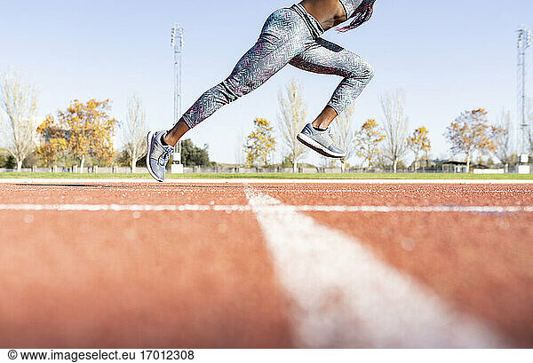 Weibliche Sportlerin  die an einem sonnigen Tag auf einer Sportbahn läuft