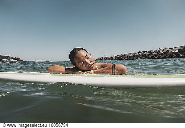 Weibliche Surferin auf Surfbrett liegend