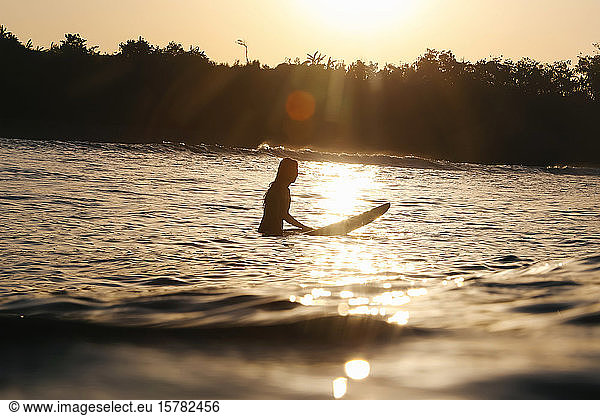 Weibliche Surferin bei Sonnenuntergang  Bali  Indonesien