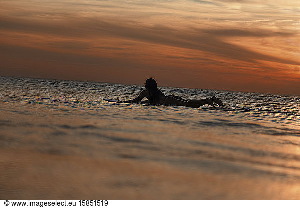 Weibliche Surferin bei Sonnenuntergang im Ozean