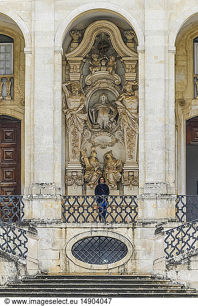 Weibliche Touristin steht vor einem verschnörkelten Gebäude im Innenhof der Universität von Coimbra; Coimbra  Bezirk Coimbra  Portugal