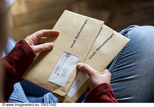 Weibliche Wählerin hält Dokumente für die Briefwahl in den Händen