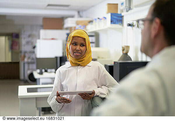 Weibliche Wissenschaftlerin im Hijab im Gespräch mit Kollegin im Labor