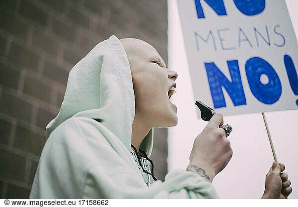 Weiblicher Aktivist schreiend mit Schild während sozialer Bewegung