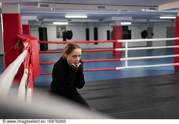 Weiblicher Boxer hockt auf dem Boxring