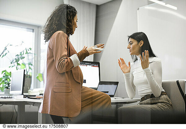 Weiblicher Chef diskutiert mit Kollege über Computer im Büro
