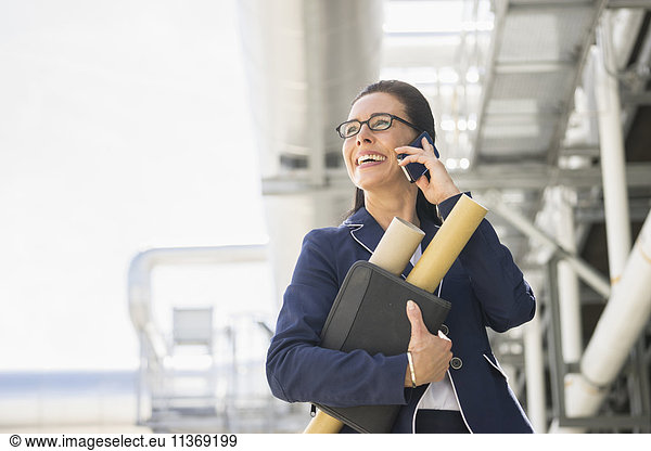 Weiblicher Ingenieur  der in einem geothermischen Kraftwerk mit einem Mobiltelefon spricht