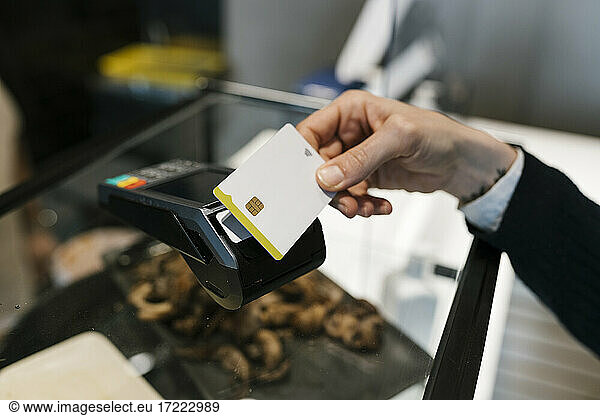 Weiblicher Kunde beim Bezahlen mit Kreditkarte in beleuchtetem Restaurant