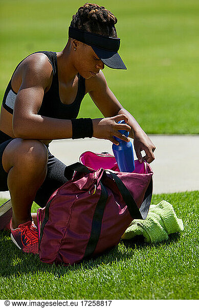 Weiblicher Leichtathlet mit Wasserflasche und Tasche