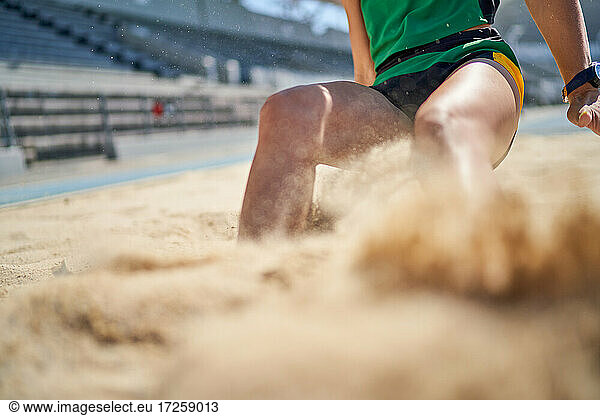 Weiblicher Leichtathletik-Weitspringer bei der Landung im Sand