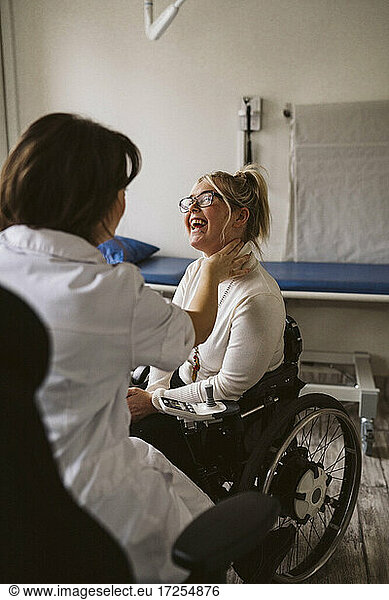 Weiblicher medizinischer Experte prüft den Puls einer lächelnden behinderten Frau in einer medizinischen Klinik