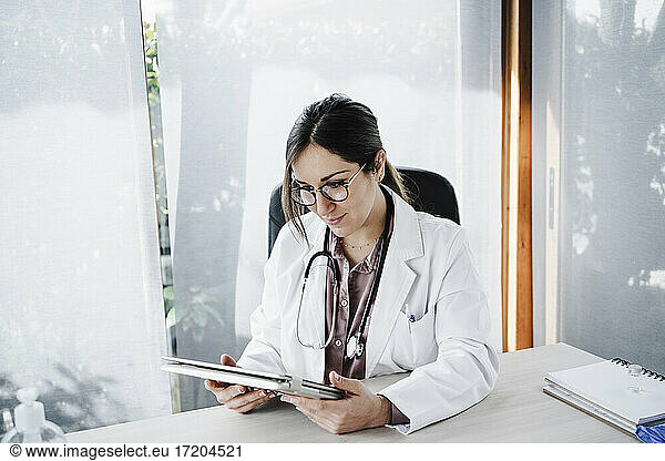 Weiblicher medizinischer Experte schaut auf ein digitales Tablet in einer medizinischen Klinik