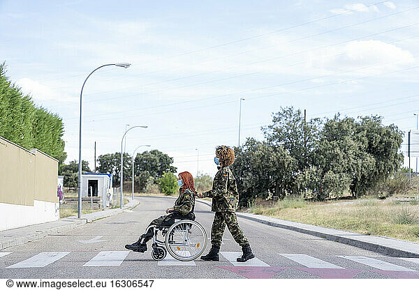 Weiblicher Militäroffizier schiebt einen im Rollstuhl sitzenden Soldaten