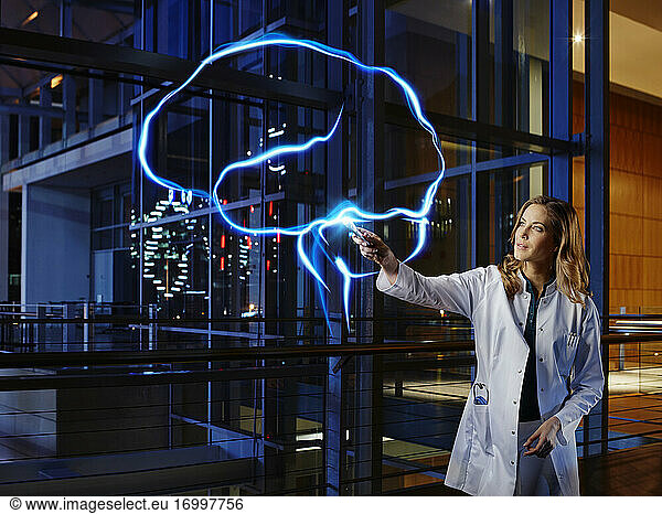 Weiblicher Neurologe analysiert Gehirn mit Lichtmalerei im Krankenhaus