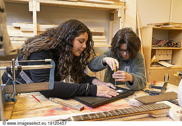 Weiblicher Techniker unterrichtet Junge bei der Reparatur von Laptops im Recyclingzentrum