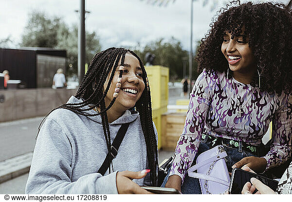 Weiblicher Teenager weibliche Freunde lachend mit Smartphone auf Gehweg