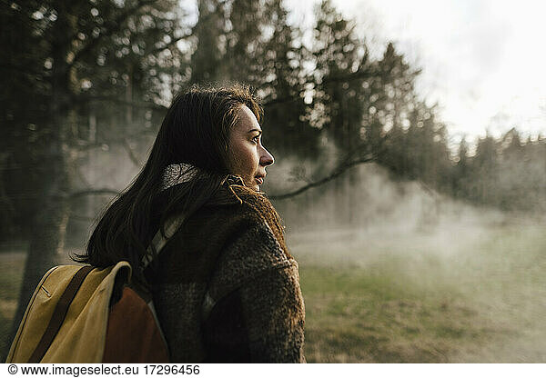 Weiblicher Wanderer erkundet Wald bei nebligem Wetter