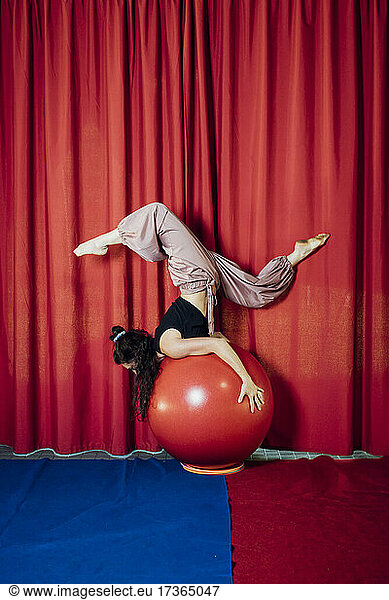 Weiblicher Zirkusartist balanciert auf rotem Ball