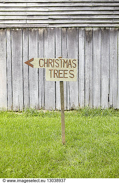 Weihnachtsbäume Text auf Informationsschild an Grasfeld gegen Zaun