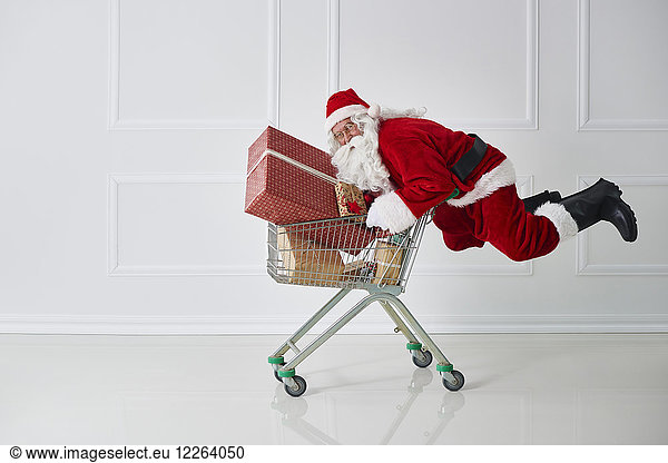 Weihnachtsmann mit Weihnachtsgeschenken mit Einkaufswagen